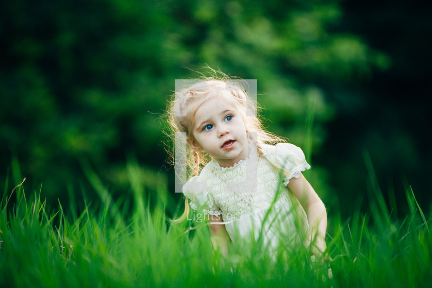 girl child playing in green grass 
