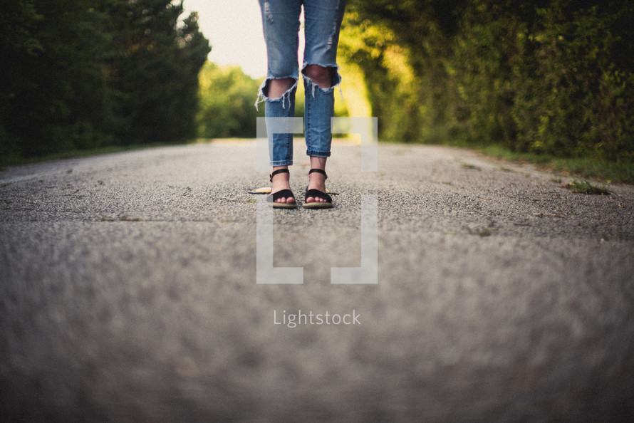girl standing in the middle of a dirt road 