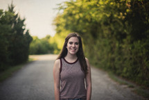 teen girl standing in the middle of a dirt road 