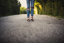 girl standing in the middle of a dirt road 