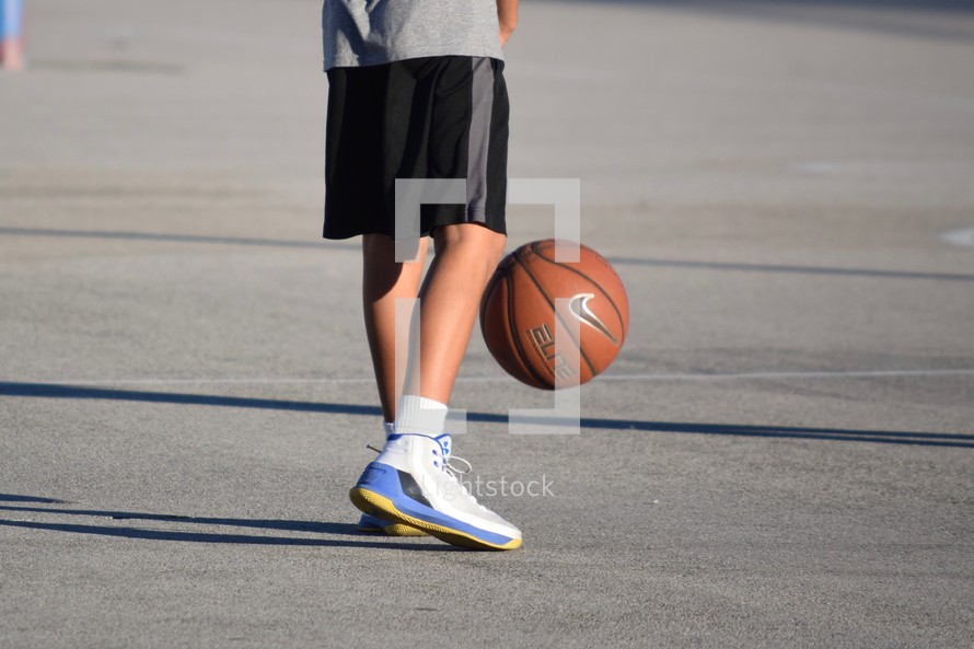 a boy on an outdoor basketball court playing ball 
