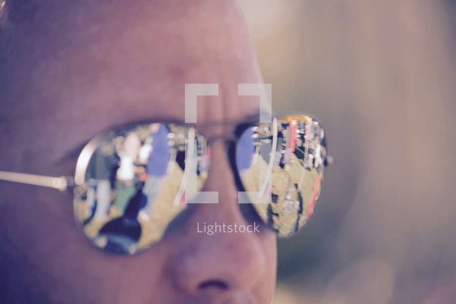 reflection of a crowd of people in a man's sunglasses 