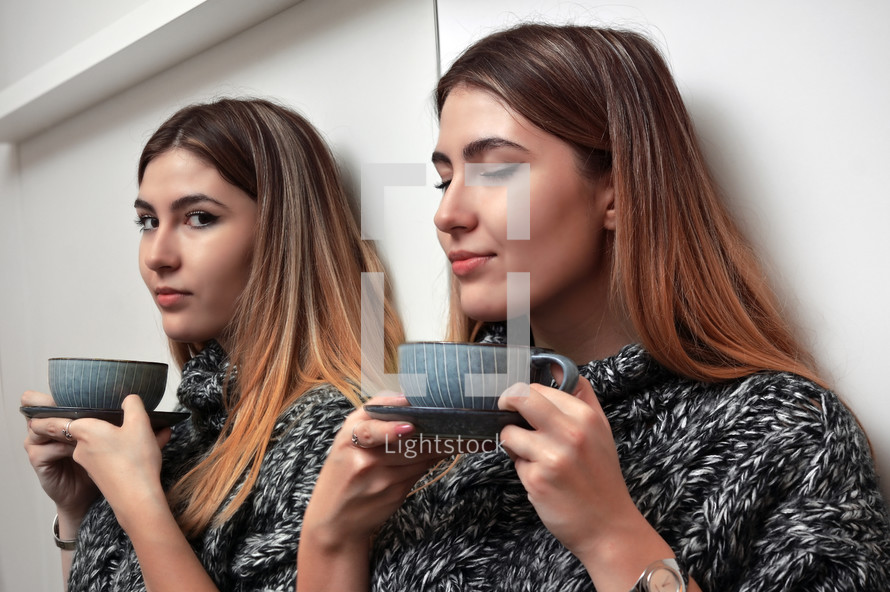 Girl With A Cup Of Hot Drink Stands In Front Of A Mirror