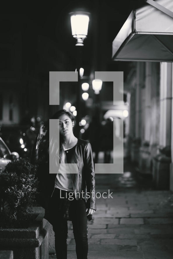 teen girl standing on a sidewalk at night 