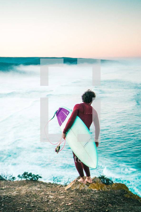 surfer standing on a beach with his surfboard 