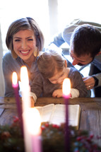 a family reading a Bible in front of an Advent wreath 