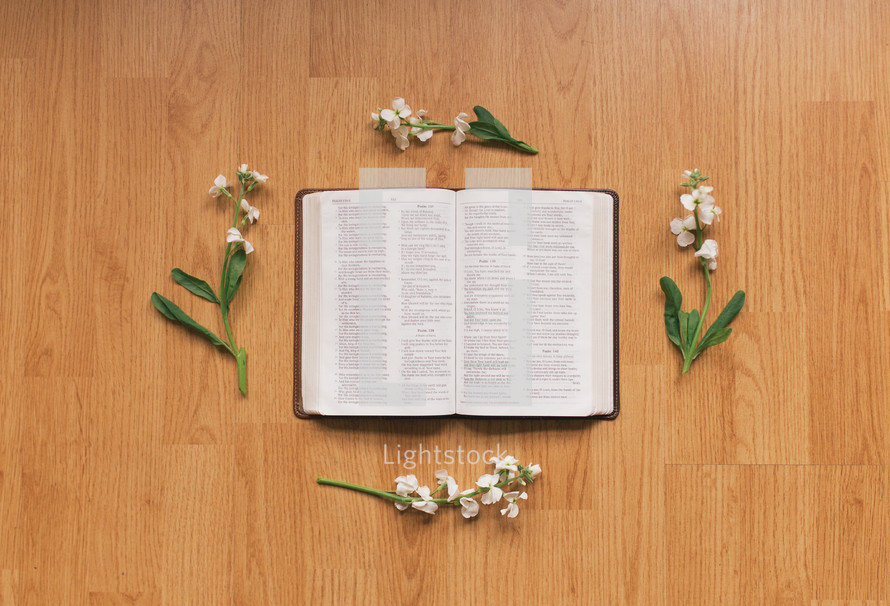 flowers and open Bible on a wooden table 