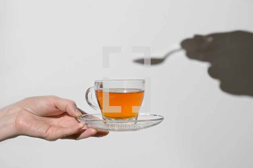 Conceptual Cup Of Tea and Shadow of Spoon and Hand