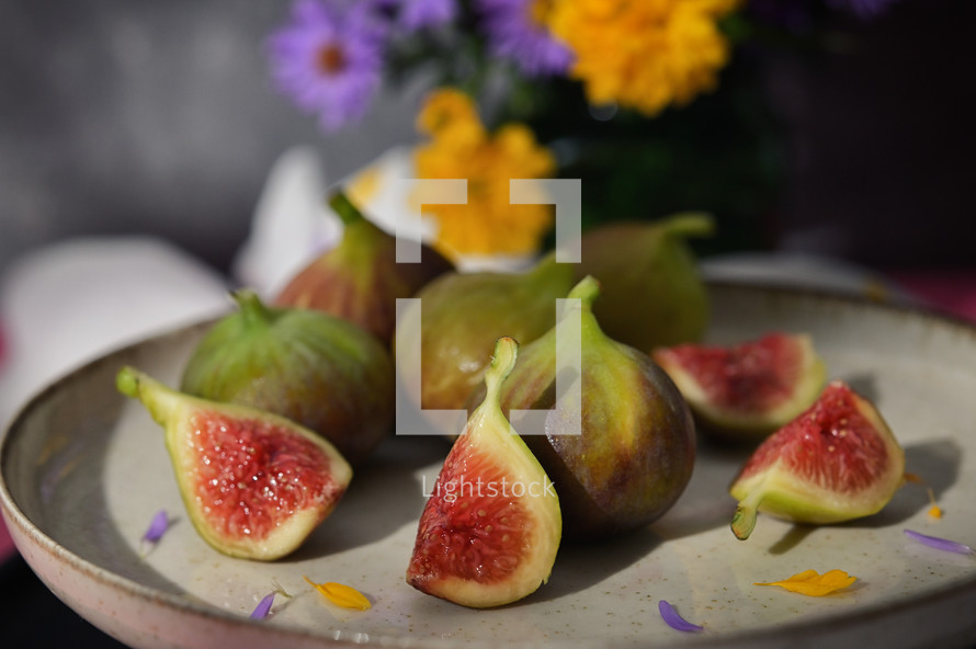 Plate of figs on table with flowers
