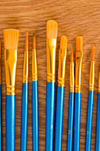 blue and gold paint brushes on  golden wood