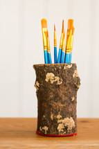 a wood can of paint brushes with a white background