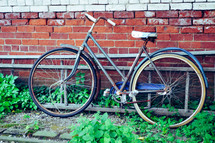 old rusty bicycle leaning against a brick wall 