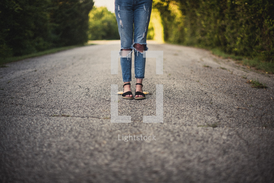 teen girl standing in the middle of a rural road 