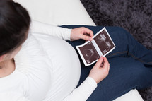 pregnant woman looking at ultrasound photos 