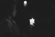 a woman holding a candle during a candlelight service 