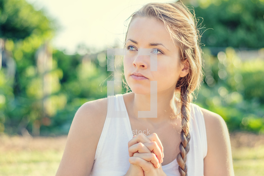 young woman praying outdoors 