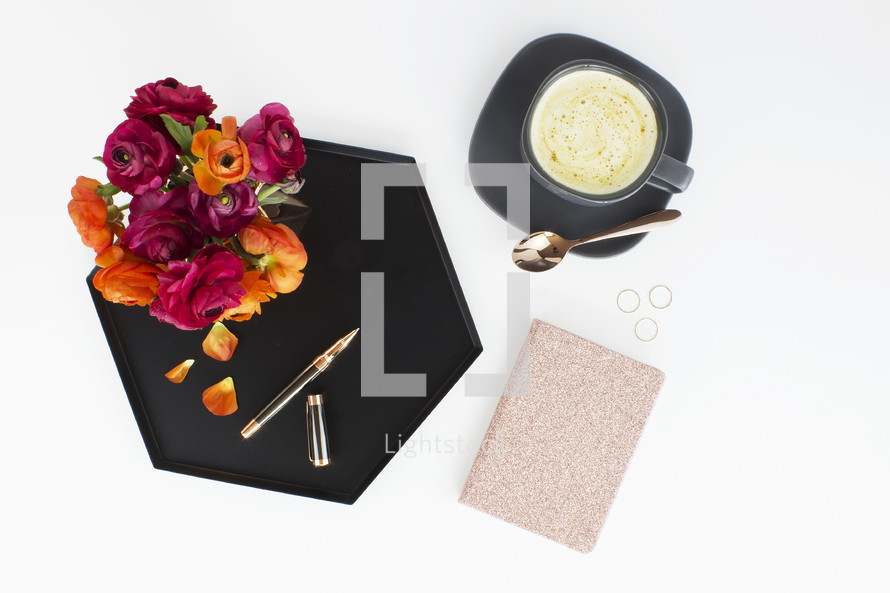 pen, tray, rose petals, notepad, and bowl of soup on a white table 