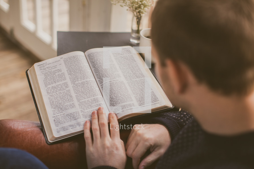 Man reading the Bible in his home with coffee.