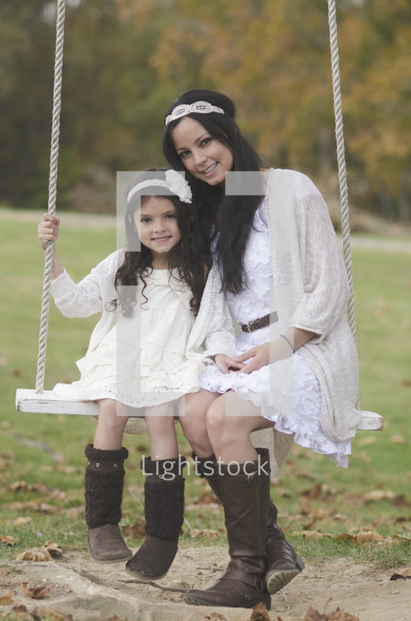 portrait of a mother and daughter on a rope swing 