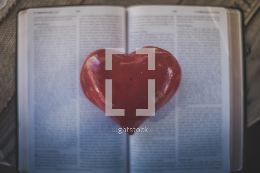 A red heart on the pages of an open Bible