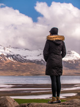 a woman looking out at snow capped mountains 