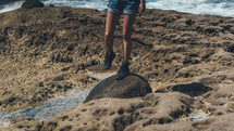 woman standing on a rock on a beach 