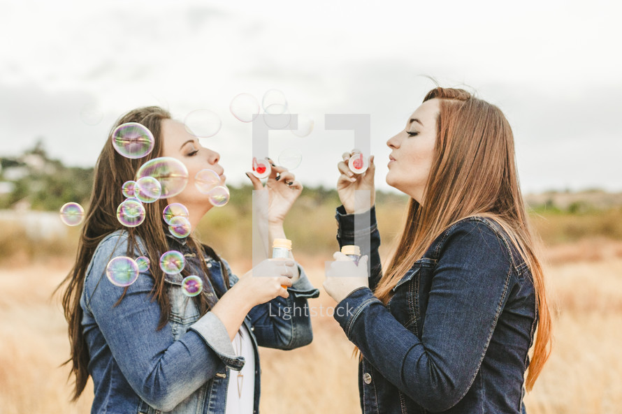 sisters blowing bubbles outdoors 