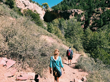 a father and teen daughter hiking a trail 