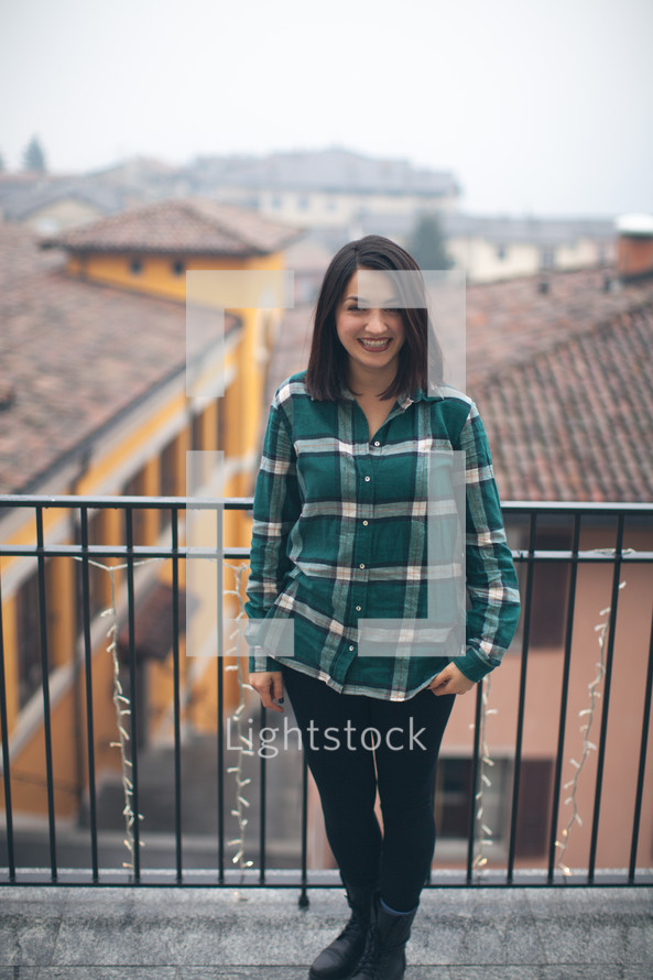 A woman in a green shirt smiling in front of a patio rail