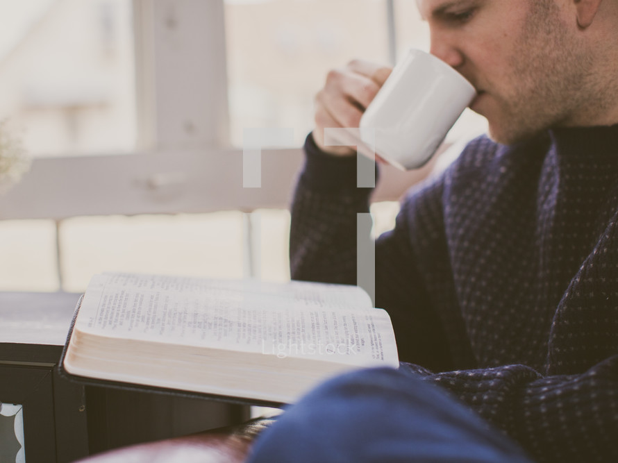 A man reading his Bible and drinking coffee