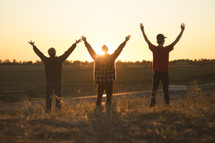 men standing in a field with raised hands 