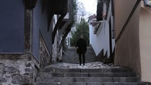 man walking down a narrow cobblestone alley 