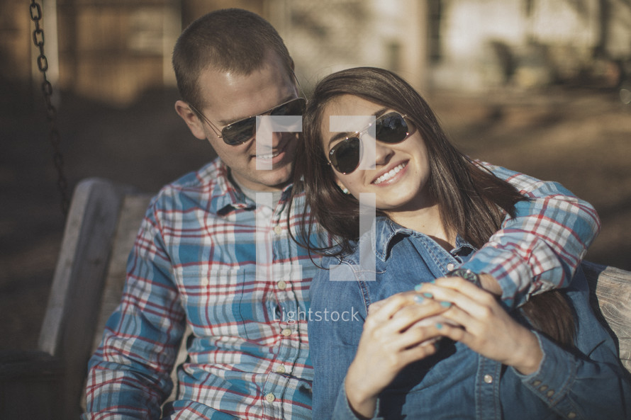 A young couple wearing sunglasses smiling together