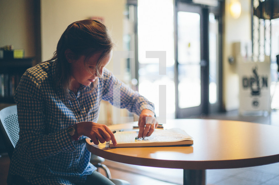 Woman writing on a pad of paper on a table in a restaurant.