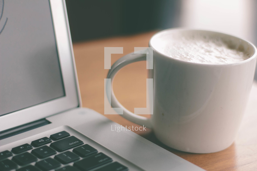 coffee cup and an open laptop 