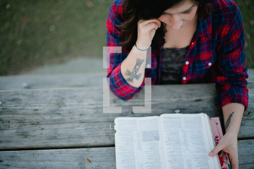 A woman reading a Bible outdoors. 