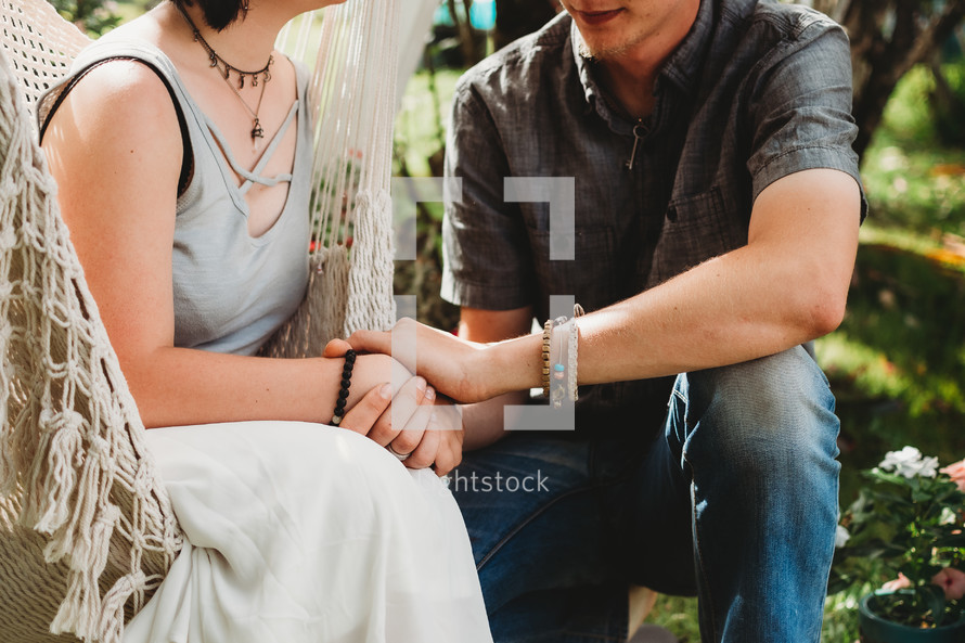 a couple holding hands sitting outdoors 