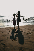 mother and daughter standing on a beach 