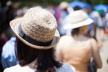 woman in a straw hat walking in a crowd 