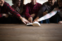 A group sitting on a couch and pointing at a Bible verse