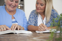 women discussing scripture and writing in a journal at a Bible study 