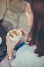 a woman holding a mug of cappuccino 