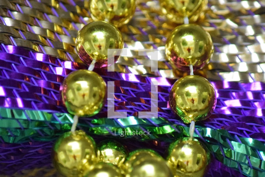 Festive Fat Tuesday beads on traditional Mardi Gras Purple, Gold, and, Green stripes 