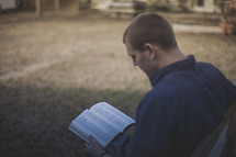 A man sitting on a bench reading the Bible