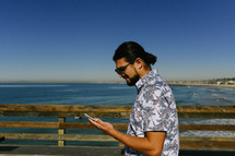 a man on a pier looking at his cellphone