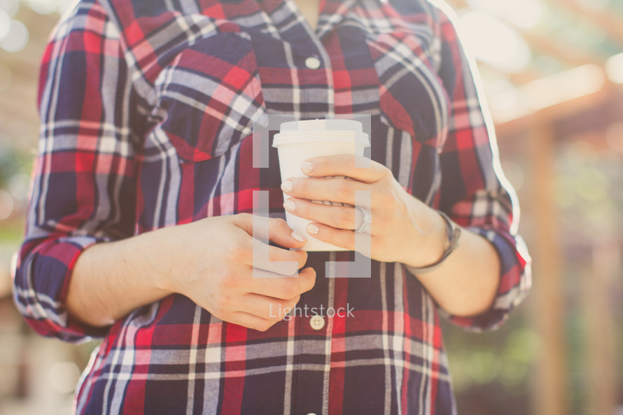 woman in a plaid shirt holding a cup of coffee 