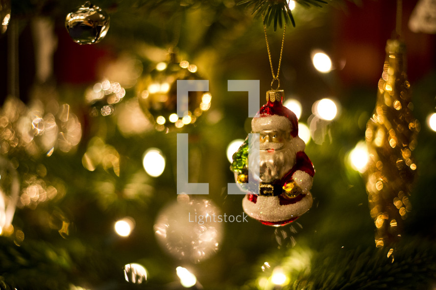 glass Santa ornament hanging on a Christmas tree