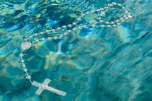 a rosary floating on turquoise water 