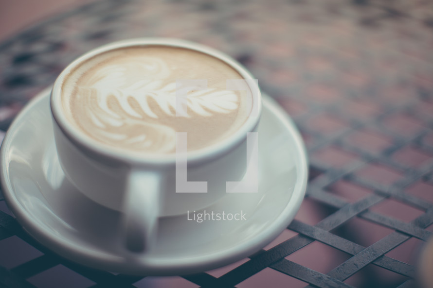 a cup of cappuccino with a leaf 