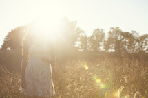 Bright sun on a young woman in a wheat field.